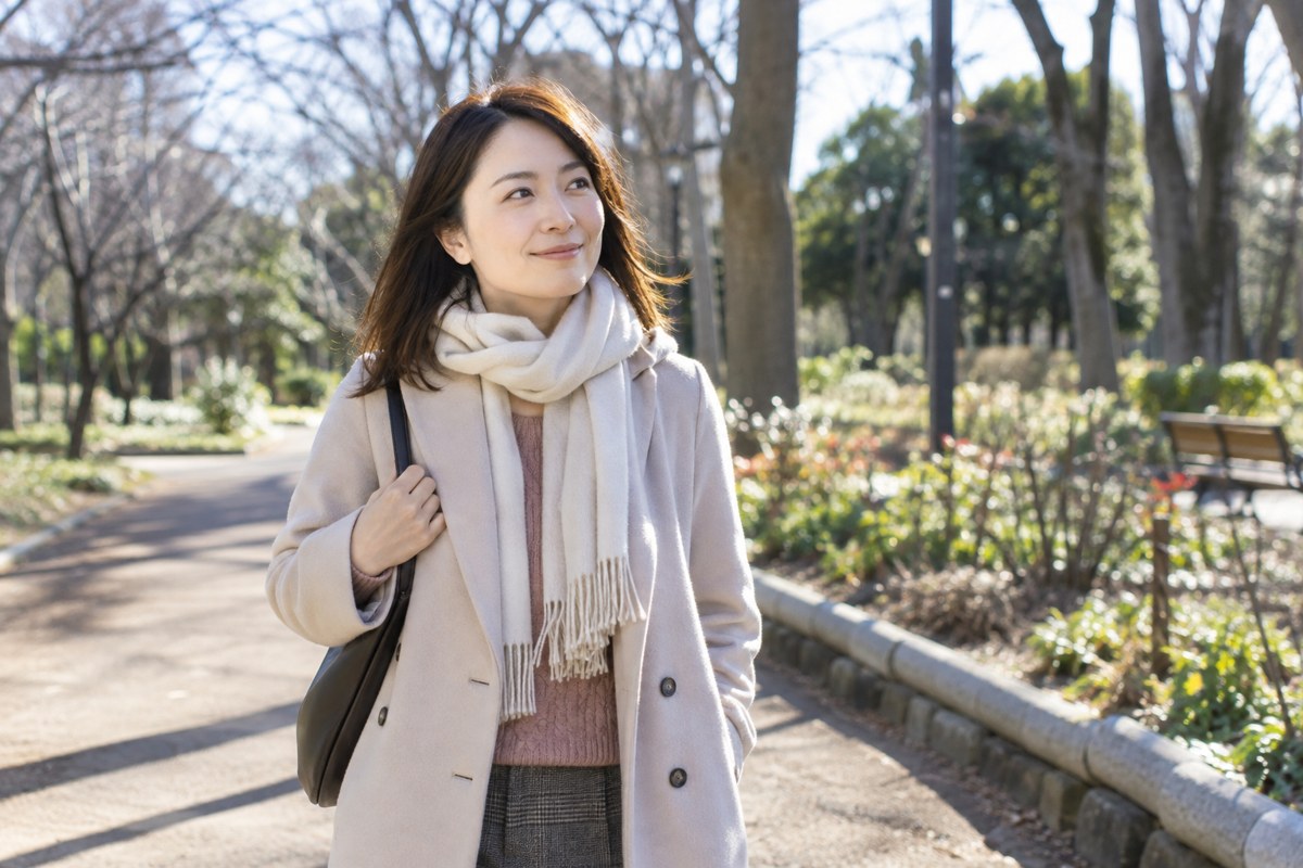 冬の公園を穏やかに歩く女性