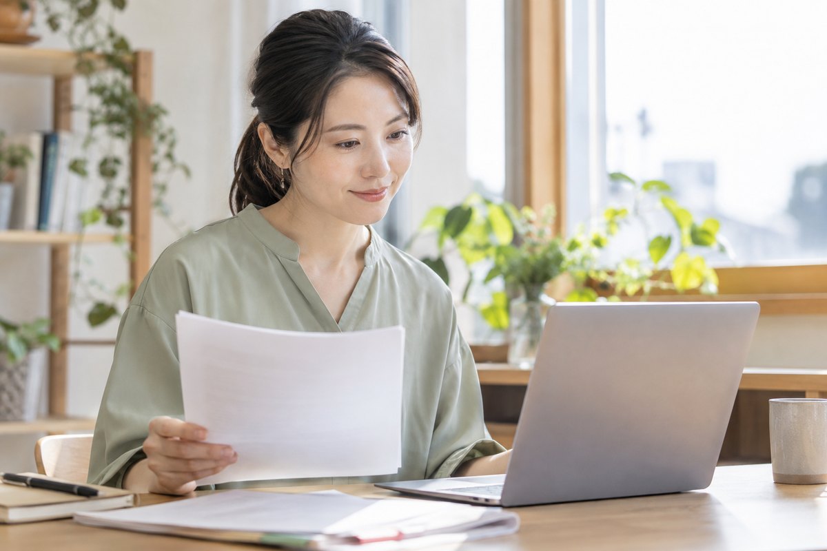 資料とパソコンで誤りを確認する女性