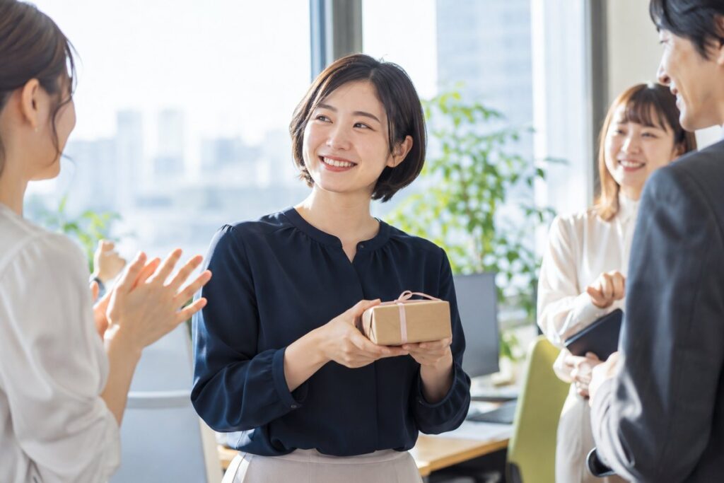小さな送別の品を手に同僚と話す女性