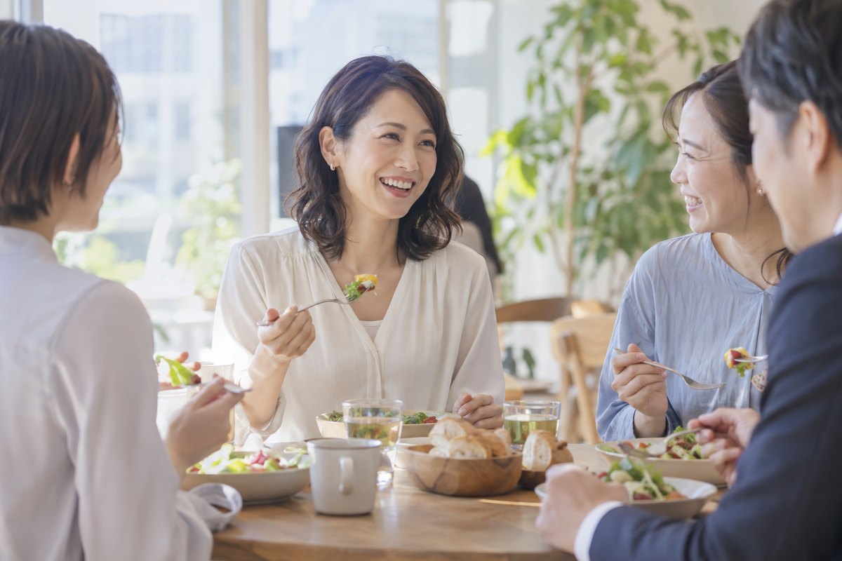 複数の同僚と食事をする女性