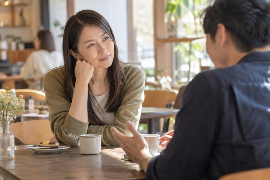 カフェで男性から交際状況を聞く女性